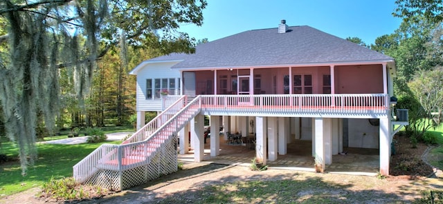 rear view of house with a wooden deck, a patio area, a sunroom, and a lawn