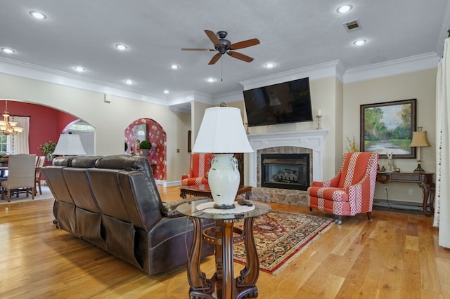 living room featuring ceiling fan with notable chandelier, light hardwood / wood-style flooring, and ornamental molding