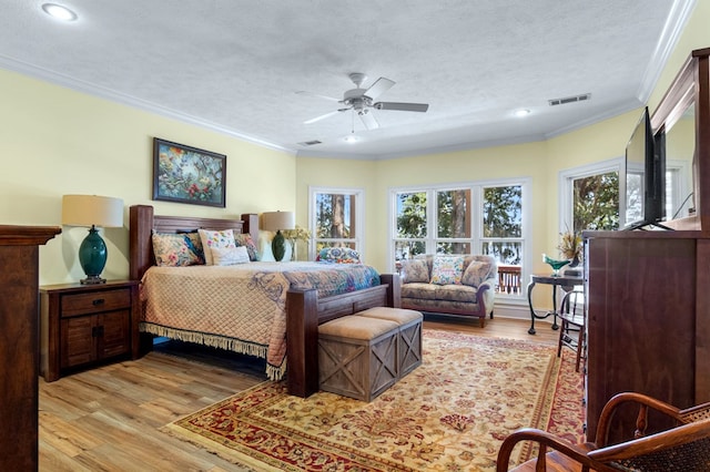 bedroom with a textured ceiling, light hardwood / wood-style flooring, ceiling fan, and ornamental molding