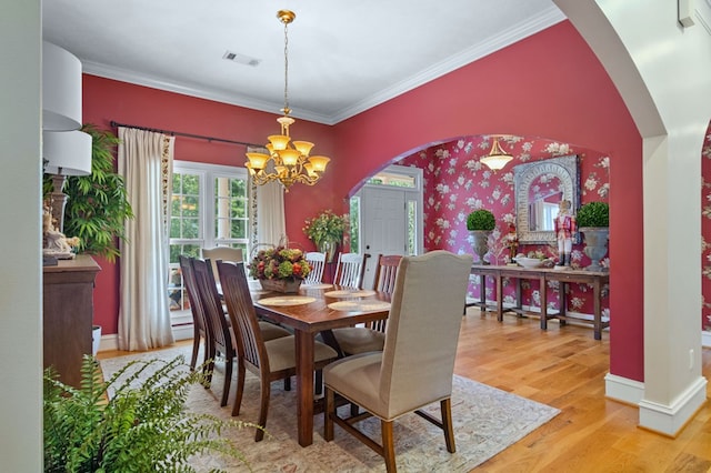 dining area with wood-type flooring, crown molding, and a notable chandelier