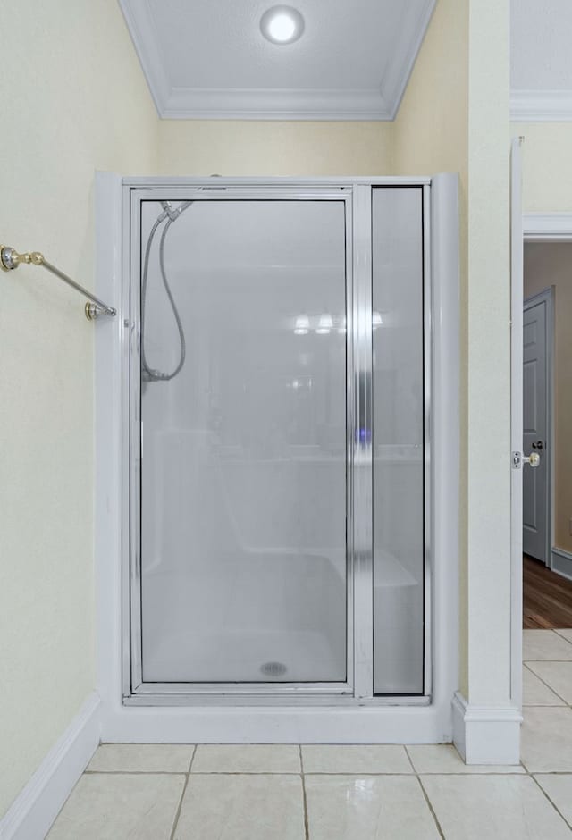 bathroom with a shower, tile patterned floors, and crown molding