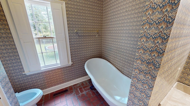 815 E 19th Ave, Cordele, GA 31015 - full bath with baseboards, wallpapered walls, a freestanding bath, toilet, and brick flooring