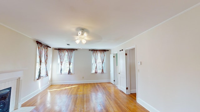 815 E 19th Ave, Cordele, GA 31015 - unfurnished living room featuring a ceiling fan, light wood-style flooring, baseboards, a tiled fireplace, and crown molding