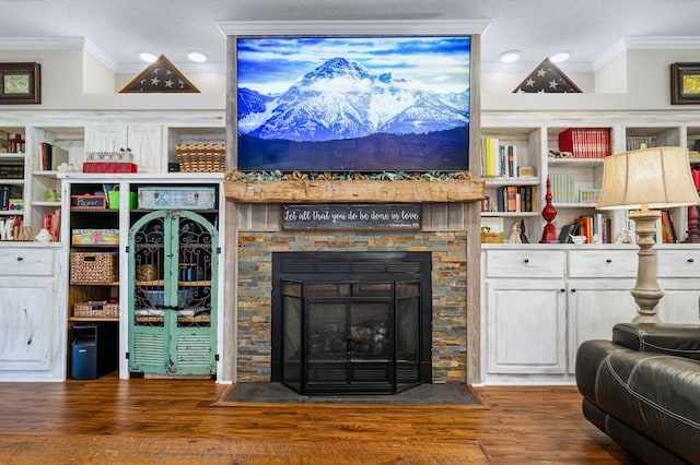 living area featuring wood finished floors, a textured ceiling, crown molding, and a stone fireplace