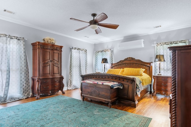 bedroom featuring a wall unit AC, visible vents, a ceiling fan, wood finished floors, and ornamental molding