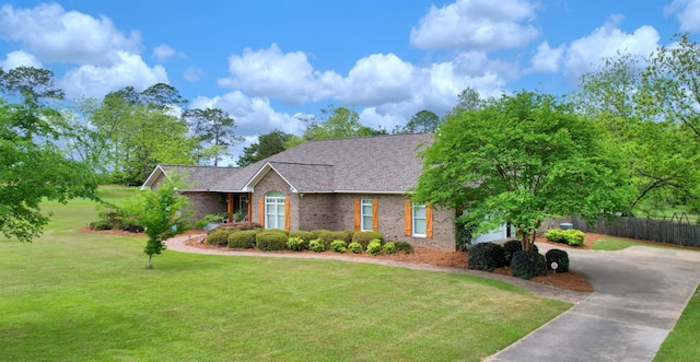 ranch-style home with a front lawn, concrete driveway, fence, brick siding, and a shingled roof