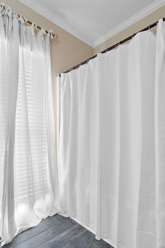 bathroom with wood finished floors, a textured ceiling, and ornamental molding