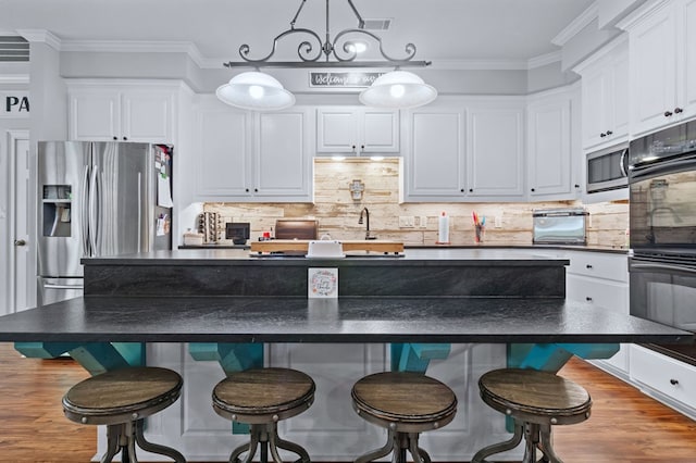 kitchen featuring ornamental molding, dark countertops, stainless steel appliances, and white cabinets