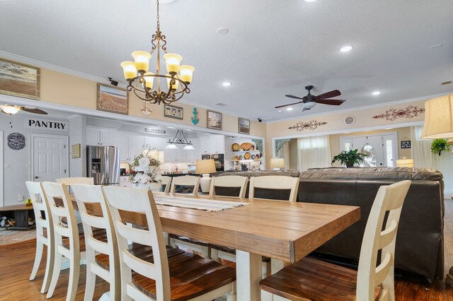 dining room with ceiling fan with notable chandelier, wood finished floors, recessed lighting, and crown molding