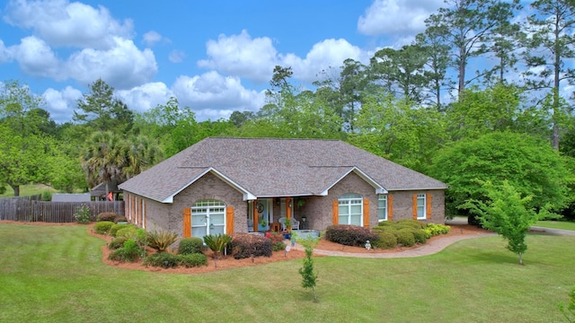 ranch-style house featuring brick siding, a front lawn, fence, and covered porch