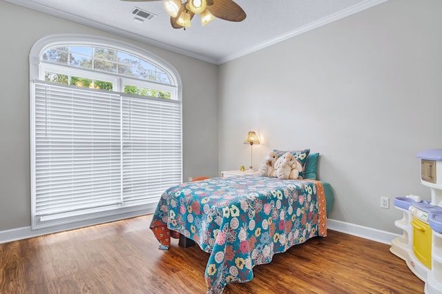 bedroom featuring wood finished floors, visible vents, a ceiling fan, ornamental molding, and baseboards