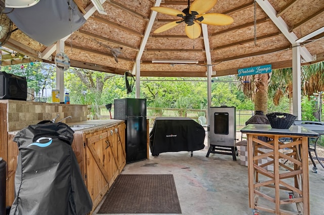 view of patio with a sink, exterior kitchen, fence, ceiling fan, and a gazebo