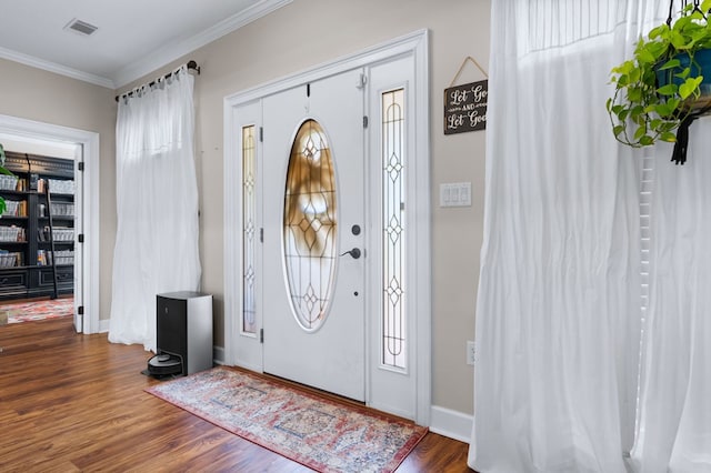 foyer with baseboards, visible vents, dark wood-type flooring, and ornamental molding