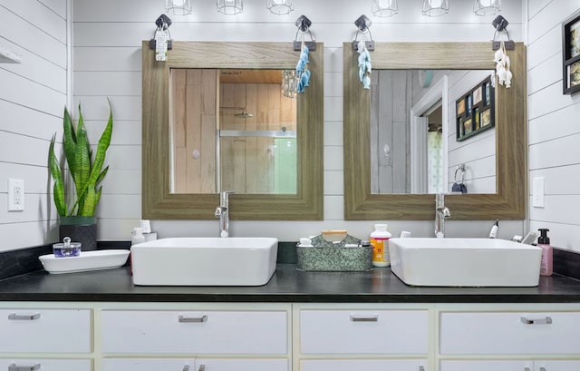 bathroom with double vanity, a shower, and a sink