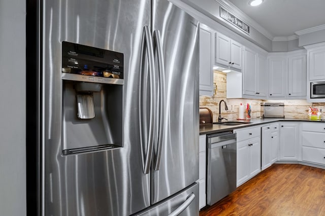 kitchen with ornamental molding, dark countertops, stainless steel appliances, and a sink