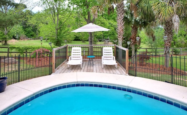 view of swimming pool with a wooden deck, a yard, a fenced in pool, and fence