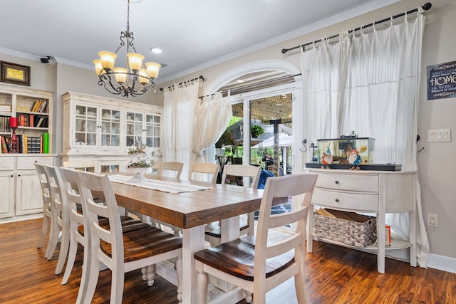 dining space featuring wood finished floors, crown molding, and a notable chandelier