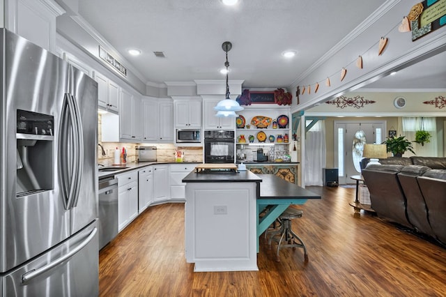 kitchen featuring open floor plan, dark countertops, appliances with stainless steel finishes, and a sink