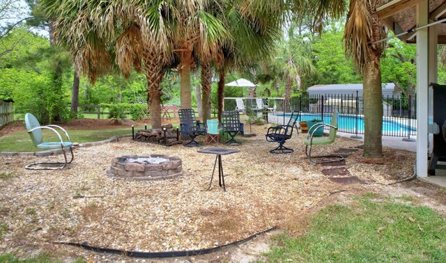 view of patio with a community pool, fence, and an outdoor fire pit