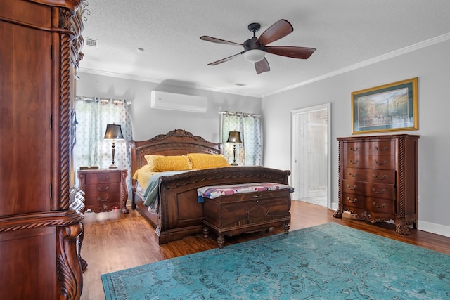 bedroom with wood finished floors, a ceiling fan, a wall unit AC, ornamental molding, and a textured ceiling