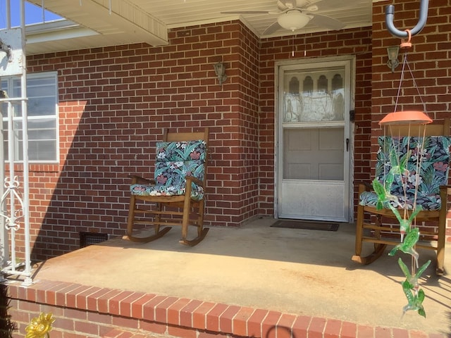 view of exterior entry with ceiling fan and brick siding