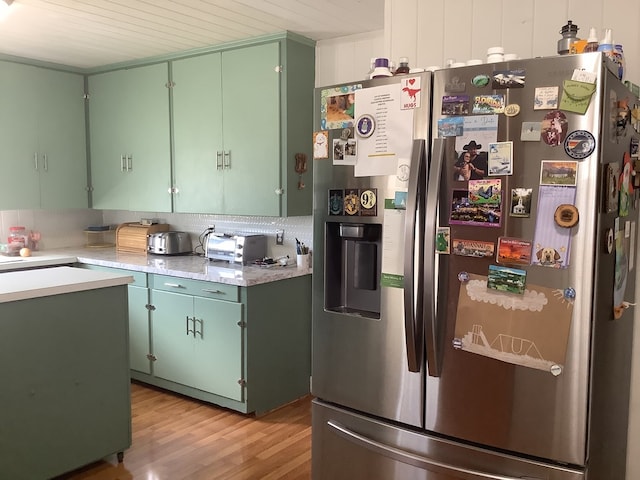 kitchen with light wood-style floors, light countertops, decorative backsplash, and stainless steel fridge with ice dispenser