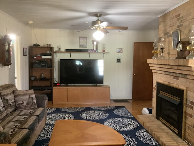 living area with a fireplace, a ceiling fan, and wood finished floors