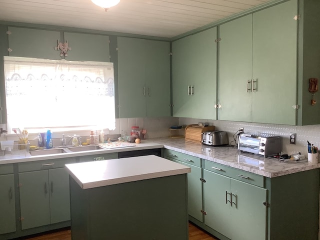 kitchen featuring a toaster, a sink, light countertops, backsplash, and a center island