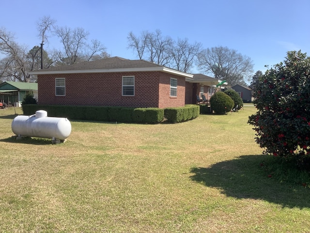 view of side of property featuring brick siding and a lawn