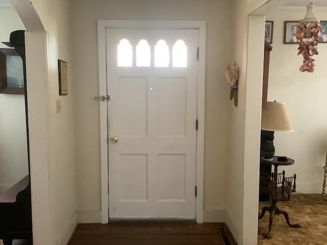 foyer entrance with arched walkways and baseboards