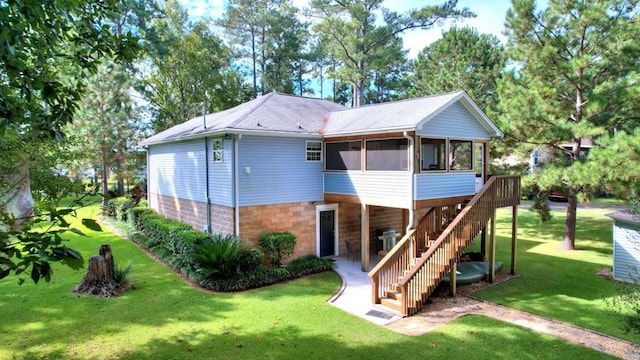 rear view of property with a sunroom, stairway, and a yard