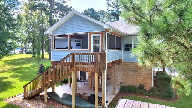 exterior space featuring a yard, a patio, a shingled roof, a sunroom, and stairs