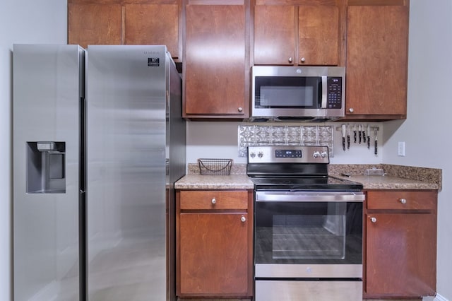 kitchen featuring stainless steel appliances, brown cabinetry, and light countertops