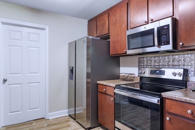 kitchen featuring baseboards, appliances with stainless steel finishes, and light wood-style floors