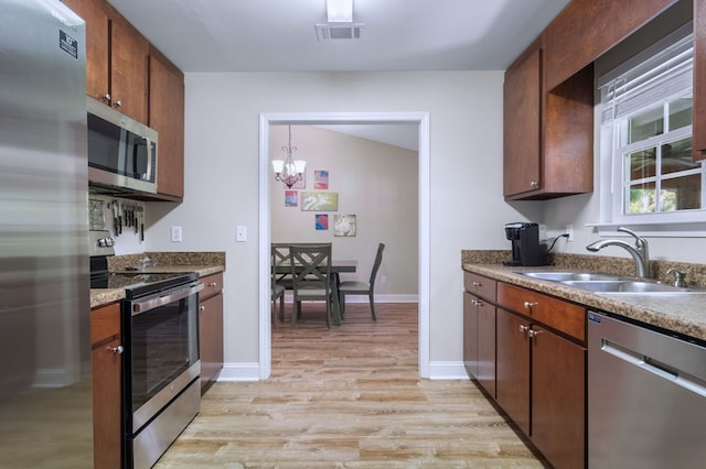 kitchen featuring an inviting chandelier, stainless steel appliances, sink, and light hardwood / wood-style flooring