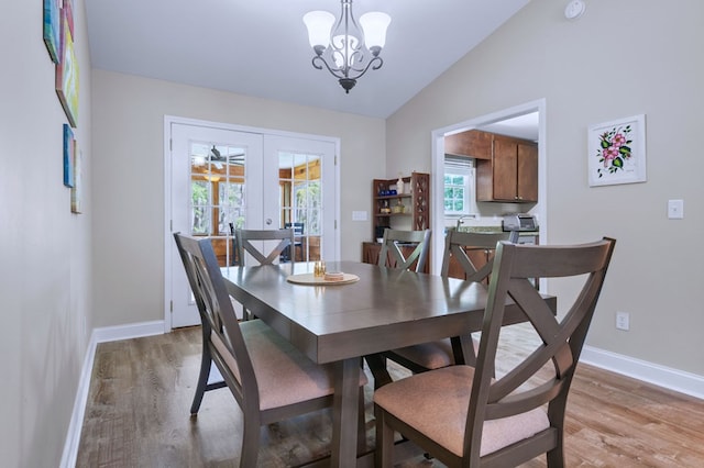 dining area with an inviting chandelier, vaulted ceiling, french doors, and wood-type flooring