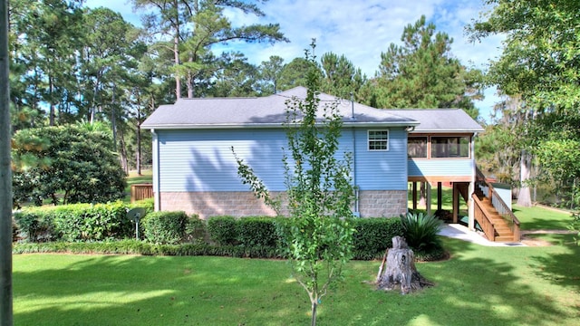 exterior space featuring a sunroom, a yard, and stairway