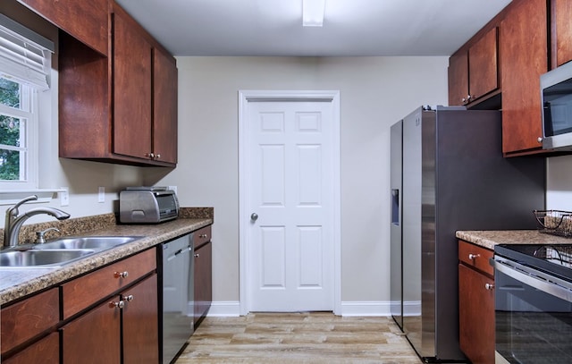 kitchen with stainless steel appliances, sink, and light hardwood / wood-style flooring