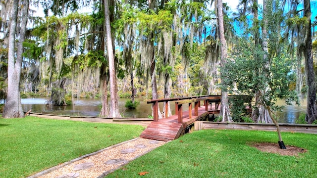 surrounding community with a water view and a lawn