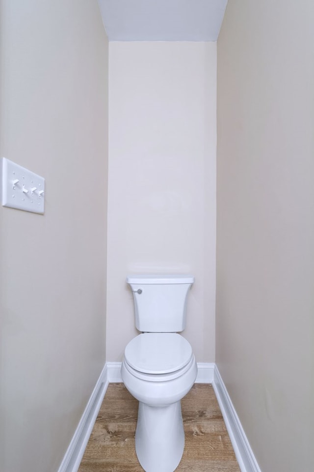 bathroom with wood finished floors, toilet, and baseboards