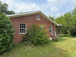 view of side of home featuring a yard and brick siding