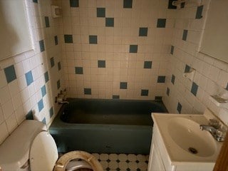 bathroom with vanity, toilet, and tile walls
