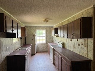 kitchen with a sink, dark countertops, electric range oven, and wallpapered walls