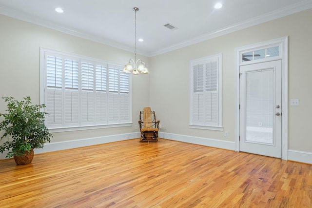 empty room featuring a notable chandelier, crown molding, and wood-type flooring