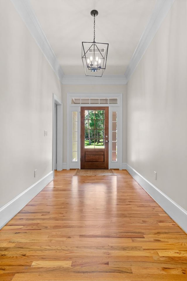 entrance foyer with an inviting chandelier, crown molding, and light wood-type flooring