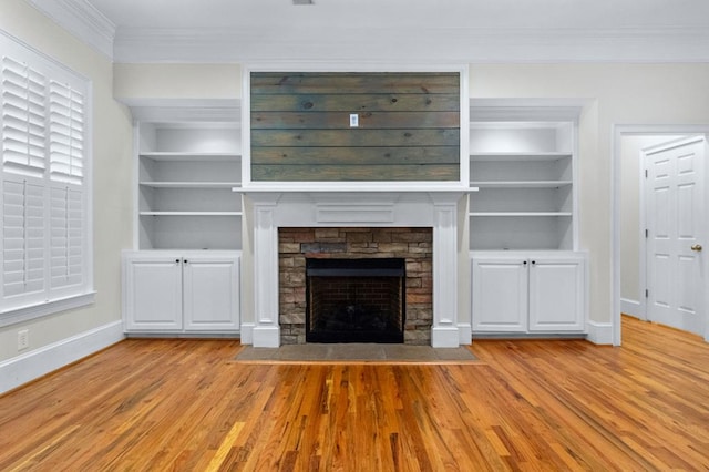 unfurnished living room featuring built in features, a stone fireplace, crown molding, and light hardwood / wood-style floors