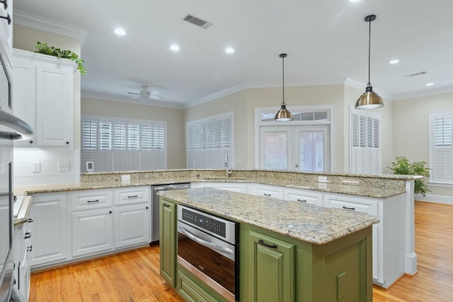 kitchen featuring white cabinets, a center island, decorative light fixtures, sink, and green cabinets