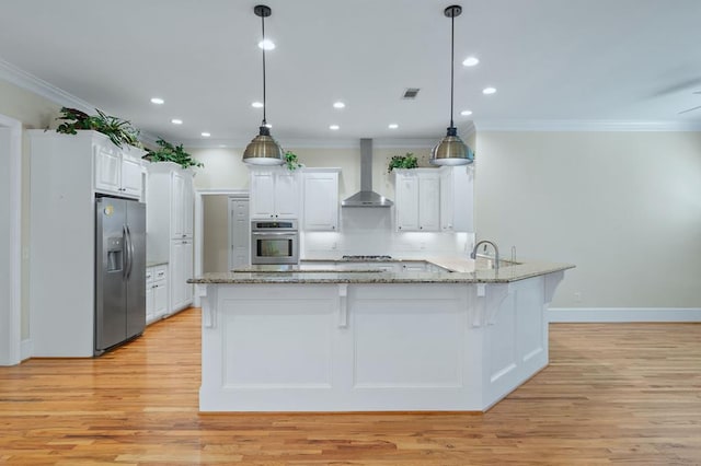 kitchen with wall chimney exhaust hood, decorative light fixtures, white cabinetry, and stainless steel appliances