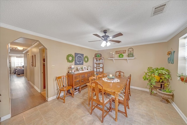 tiled dining room with ornamental molding, a textured ceiling, and ceiling fan