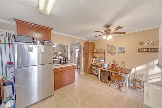 kitchen with crown molding, stainless steel appliances, ceiling fan, and a textured ceiling